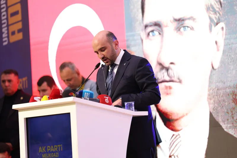 Tayyar Şahin, Türk bayrağı ve Atatürk portresi önünde kürsüde konuşurken