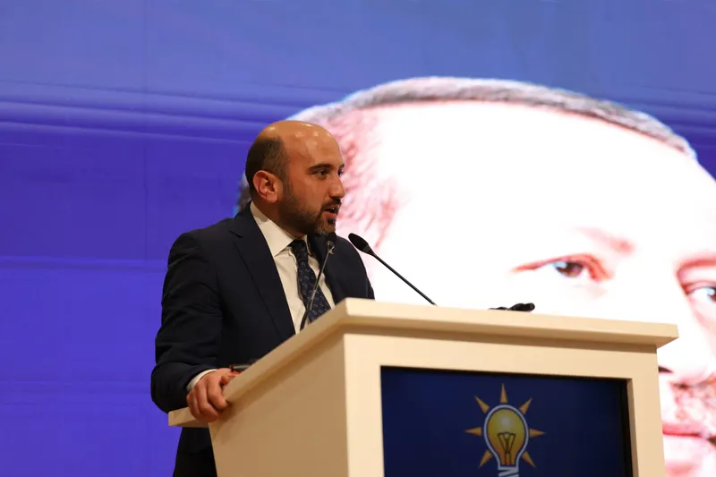 Tayyar Şahin kürsüde konuşurken, arkasındaki ekranda Cumhurbaşkanı Recep Tayyip Erdoğan'ın portresi